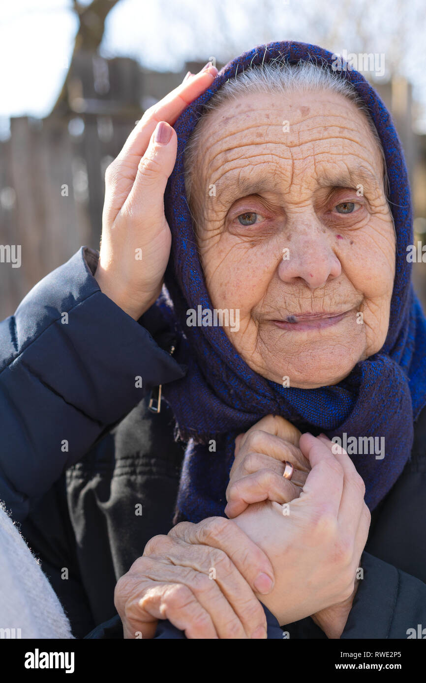 Portrait d'une vieille femme de race blanche et les mains de l'aidant en plein air - soutien, d'amour, de soins Banque D'Images