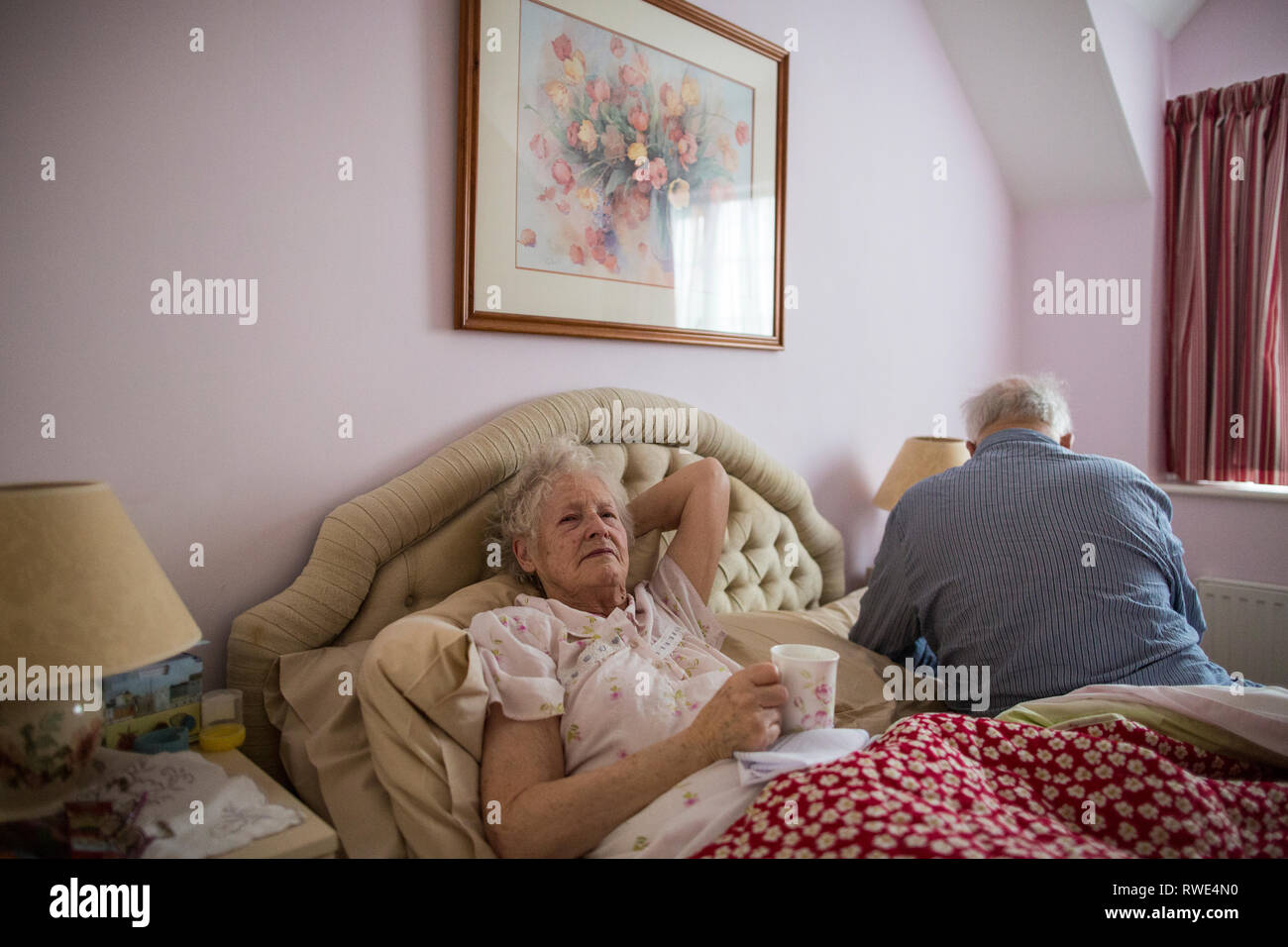 Couple de personnes âgées de plus de 80 ans dans leur chambre à coucher à la maison porter leur pyjama au matin, l'Angleterre, Royaume-Uni Banque D'Images