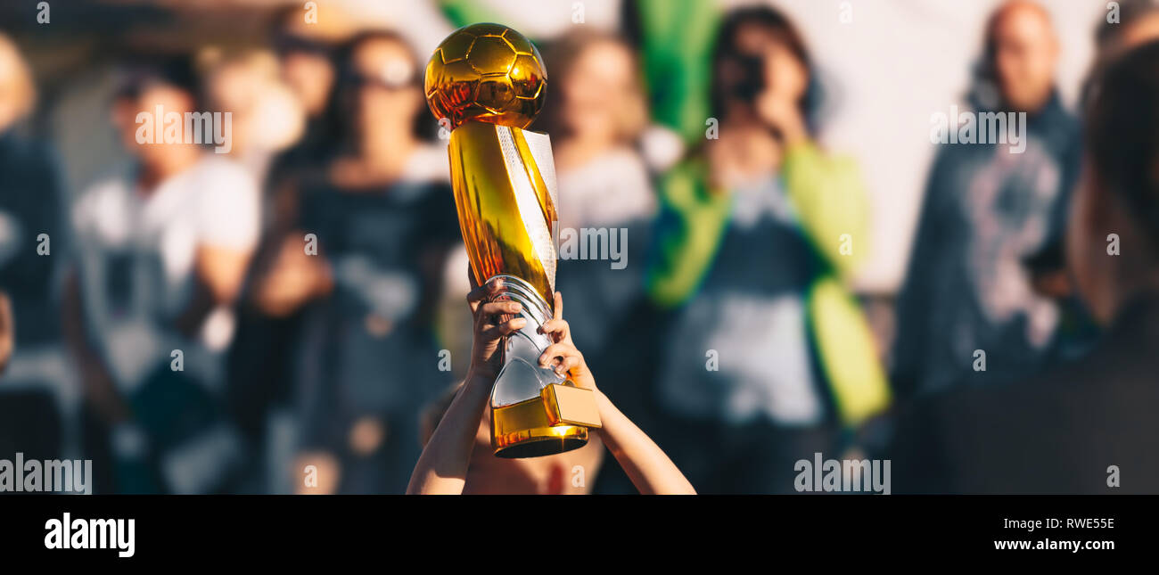 Boy Rising Golden Soccer Football Cup. Jeune footballeur Holding Up un trophée pour l'équipe gagnante. Les enfants de l'école des Champions Tournoi de Football Banque D'Images