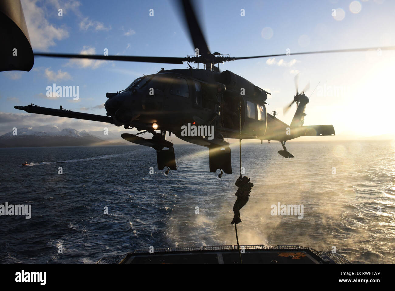 Un membre de la Sécurité maritime de la Garde côtière canadienne de l'équipe de réponse rapide de l'Ouest-cordes à partir d'un 176e Escadre, 210e Escadron de sauvetage en Alaska Air National Guard UH-60G Pave Hawk sur le pont de la garde-côte de Alex Haley (WMEC 39) dans le cadre d'un exercice à Chiniak Bay, Alaska, le 23 février 2019. Les membres de l'équipe sont formés et sont techniquement compétents dans les techniques de pointe avec les gouvernements fédéral, des états et des partenaires locaux pour protéger le pays contre les menaces en mer et dans l'air. U.S. Coast Guard photo de Maître de 3e classe Lauren Dean. Banque D'Images