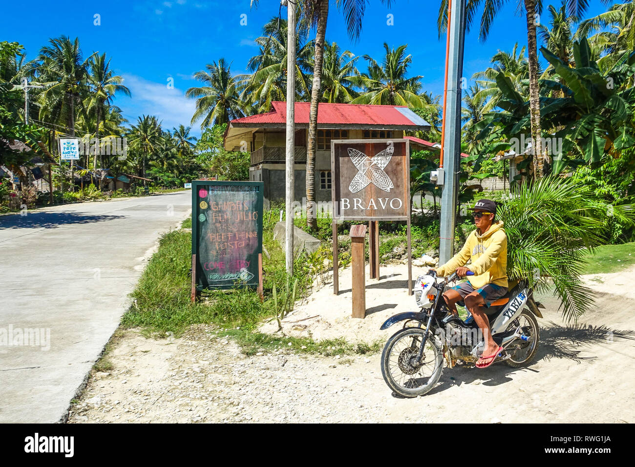 L'homme sur moto avec Resort signes et de palmiers tropicaux - Siargao, Philippines Banque D'Images