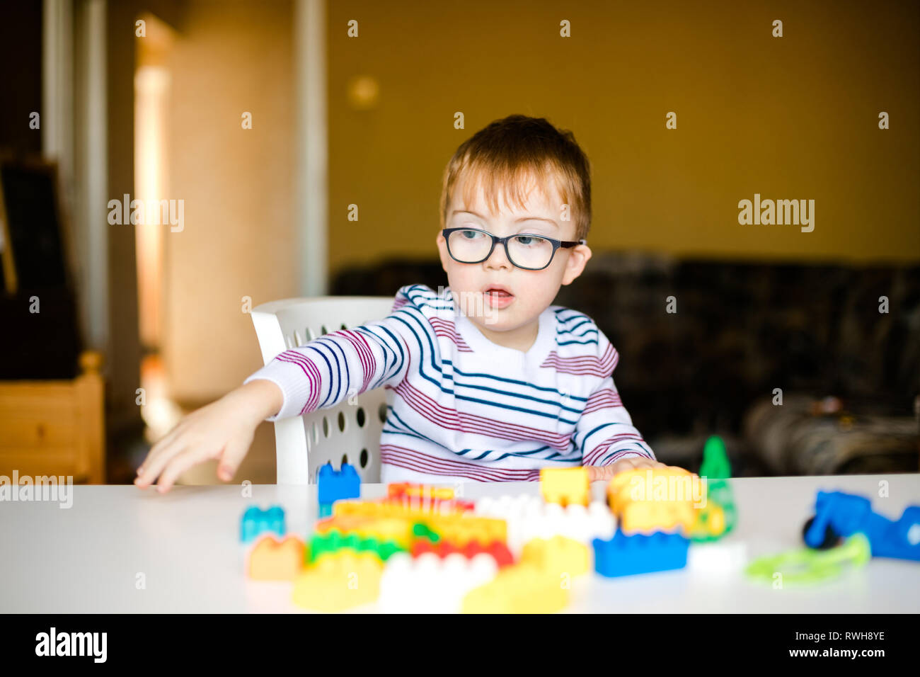 Petit Bebe Garcon Avec Le Syndrome Avec De Grandes Lunettes Bleu Jouant Avec Des Briques Colorees Photo Stock Alamy