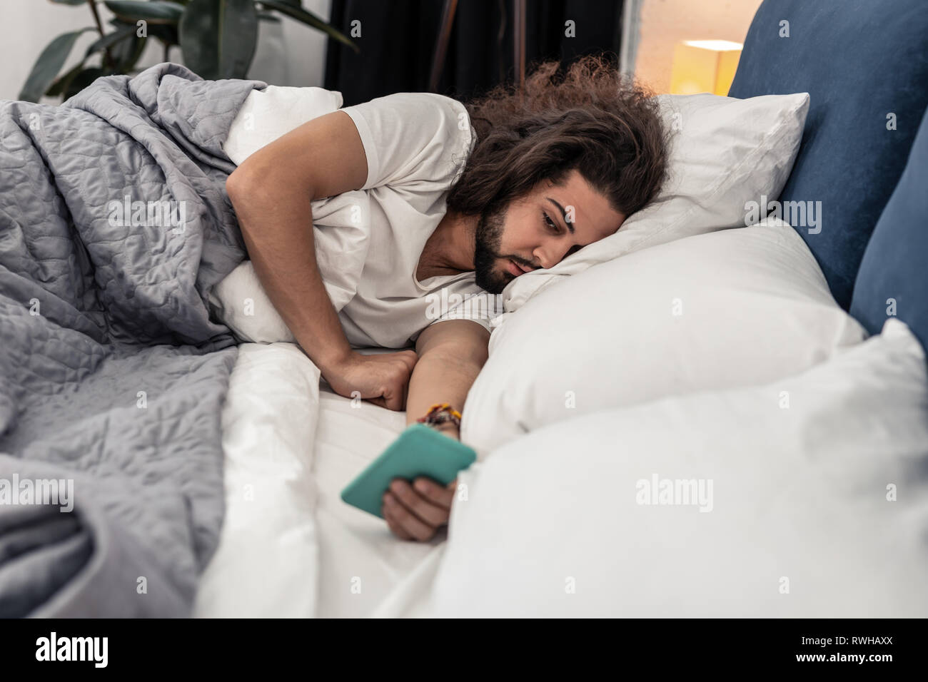 Sleepy barbu vérifier ses messages dans la matinée Banque D'Images