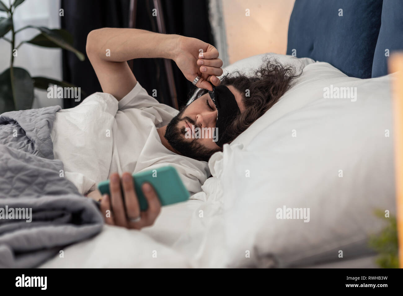 Sleepy barbu tenant son gadget mobile Banque D'Images