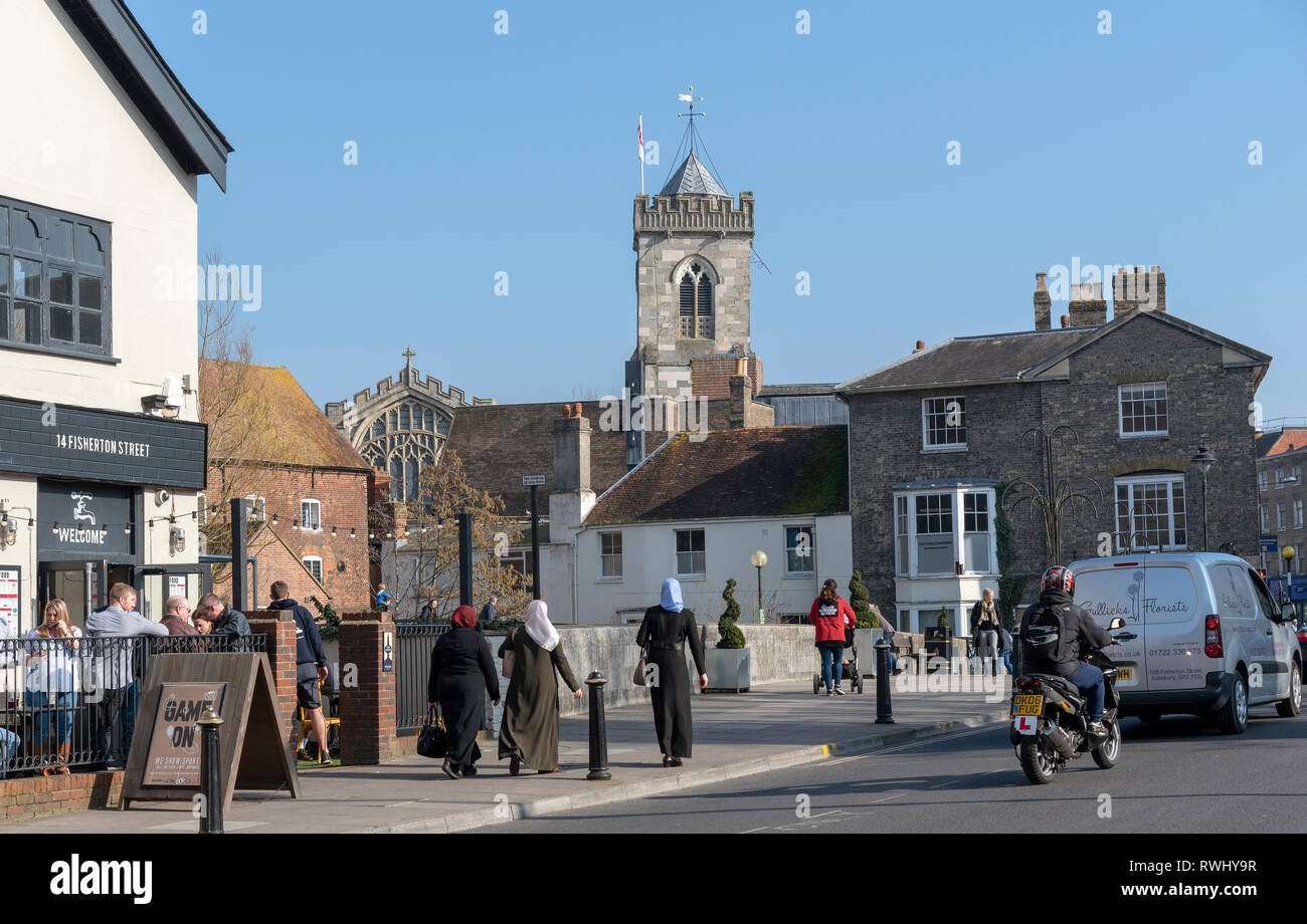 Salisbury, Wiltshire, Angleterre, Royaume-Uni. Février 2019. Femme musulmane en longues robes noires et toile de fond de l'église St Thomas. Banque D'Images