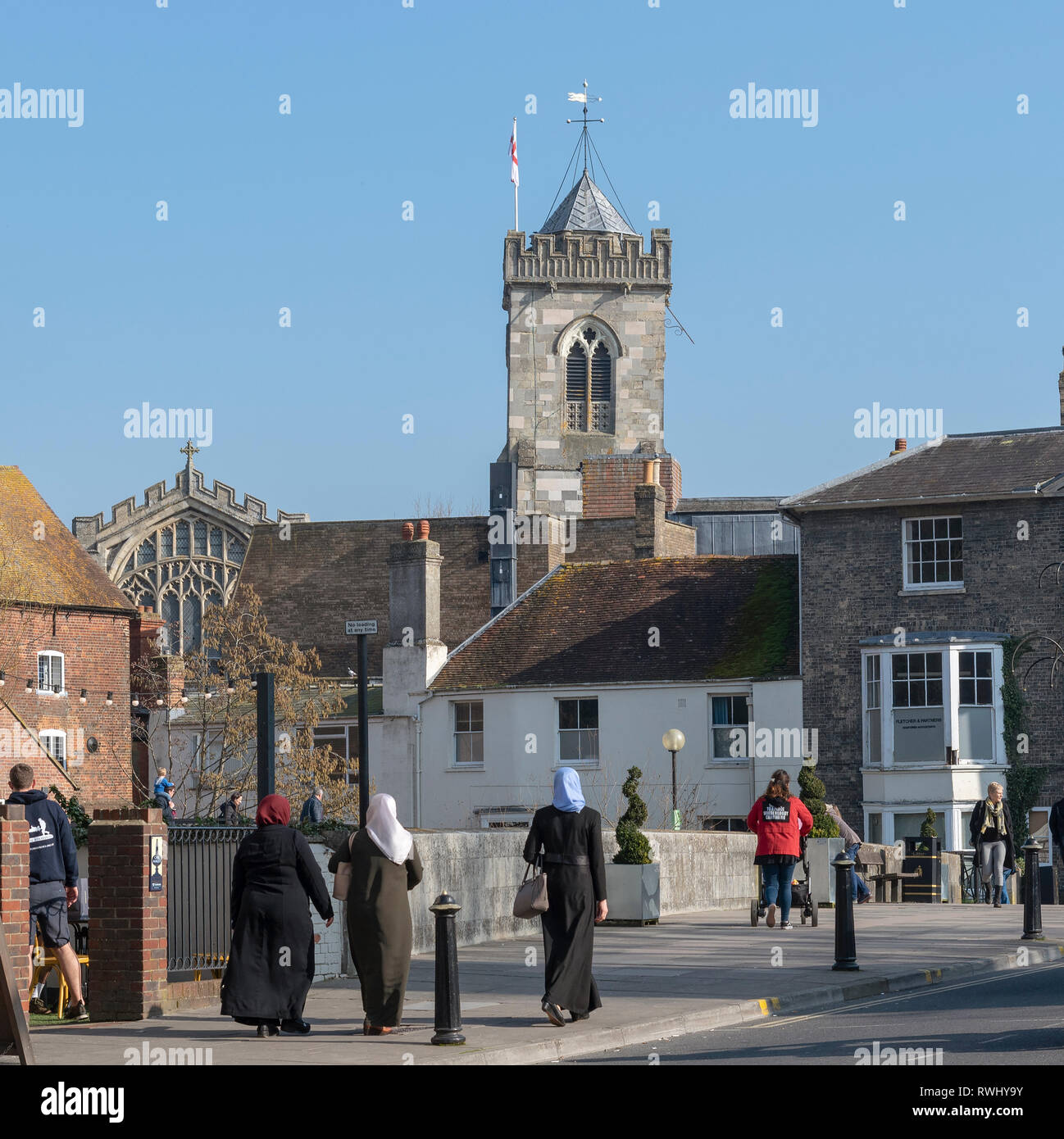 Salisbury, Wiltshire, Angleterre, Royaume-Uni. Février 2019. Femme musulmane en longues robes noires et toile de fond de l'église Saint-Thomas. Banque D'Images