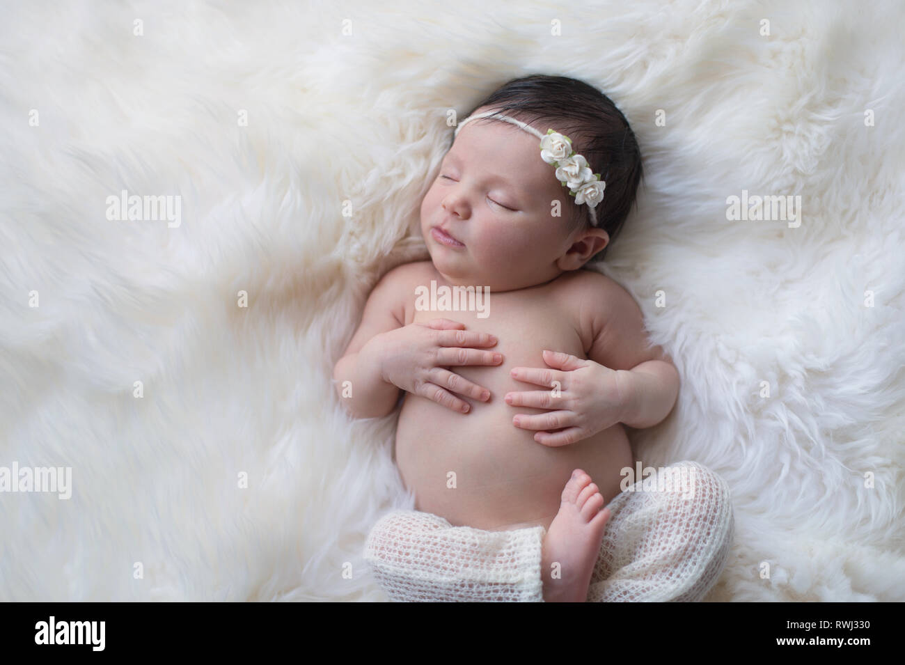 Dormir, semaine Naissance bebe Fille portant des pantalons en tricot blanc  et un bandeau rose de papier. Tourné en studio sur un tapis en peau de  mouton blanc Photo Stock - Alamy