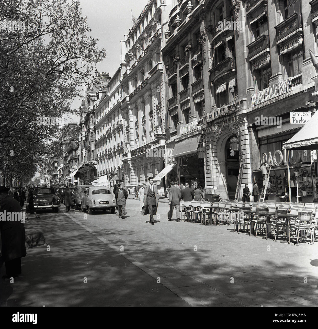 1950s, Paris, France, une petite rue à côté de l'avenue des champs Elysées avec des bureaux, des boutiques et des cafés au niveau de la rue et des voitures de l'époque garées. Banque D'Images