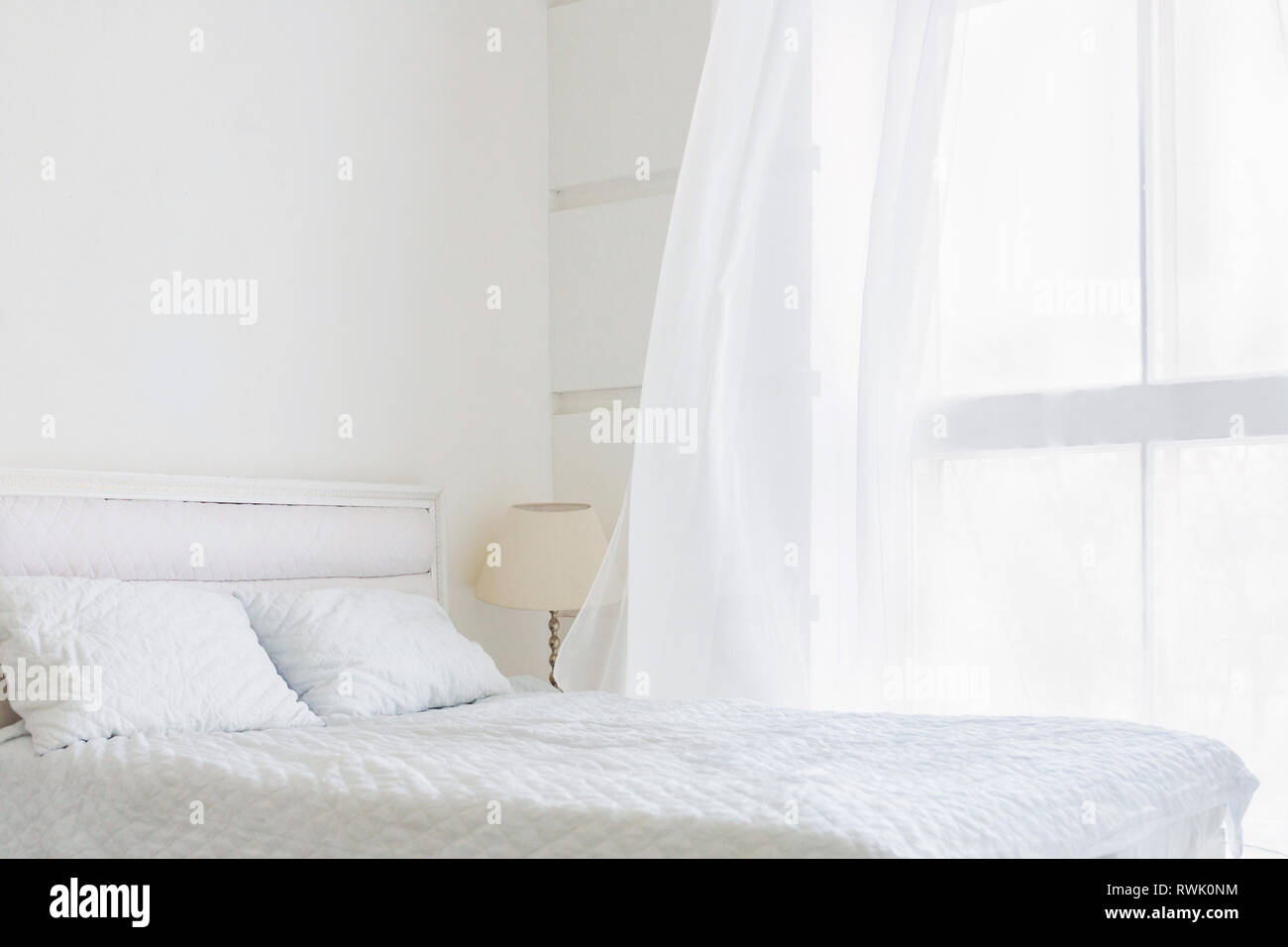 Chambre blanche intérieur minimal avec lit blanc, grande fenêtre avec des rideaux blancs Banque D'Images