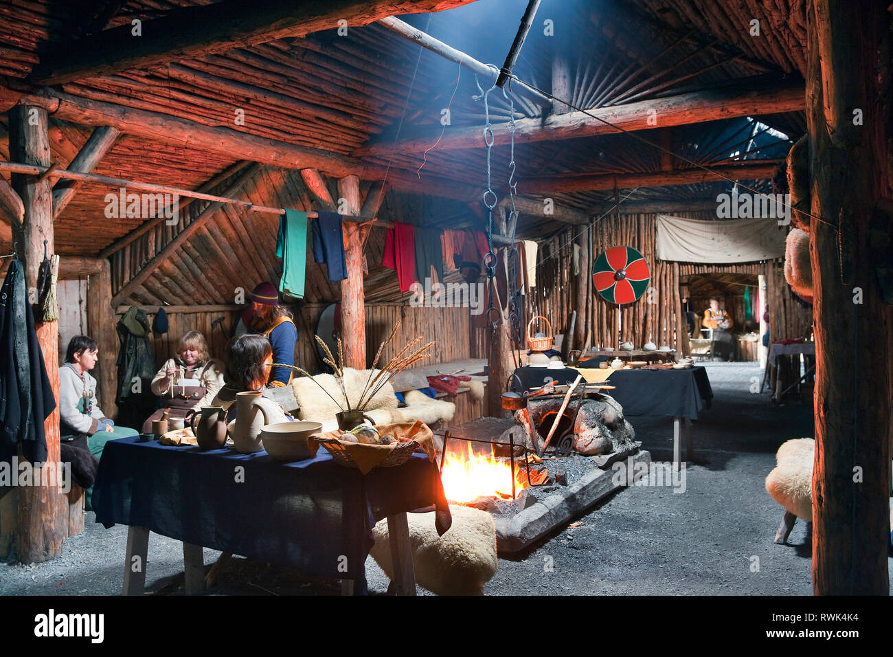 Reenactors en costumes d'effectuer des tâches traditionnelles à l'intérieur d'une maison longue Viking recréé à Norstead Village Viking et le port de commerce, DE L'Anse aux Meadows, Terre-Neuve, Canada Banque D'Images
