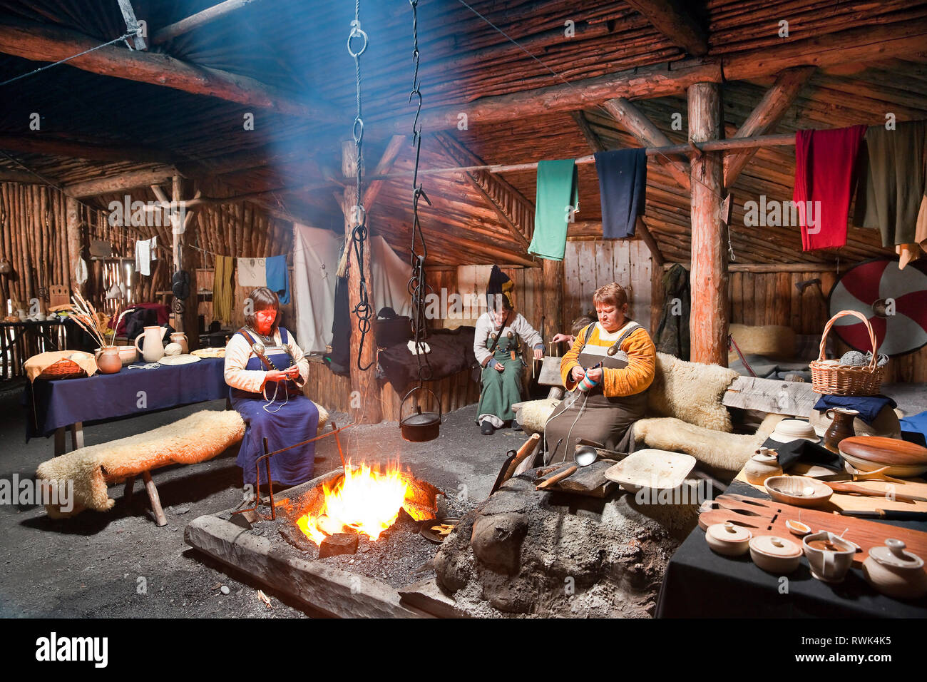 Reenactors en costumes d'effectuer des tâches traditionnelles à l'intérieur d'une maison longue Viking recréé à Norstead Village Viking et le port de commerce, DE L'Anse aux Meadows, Terre-Neuve, Canada Banque D'Images
