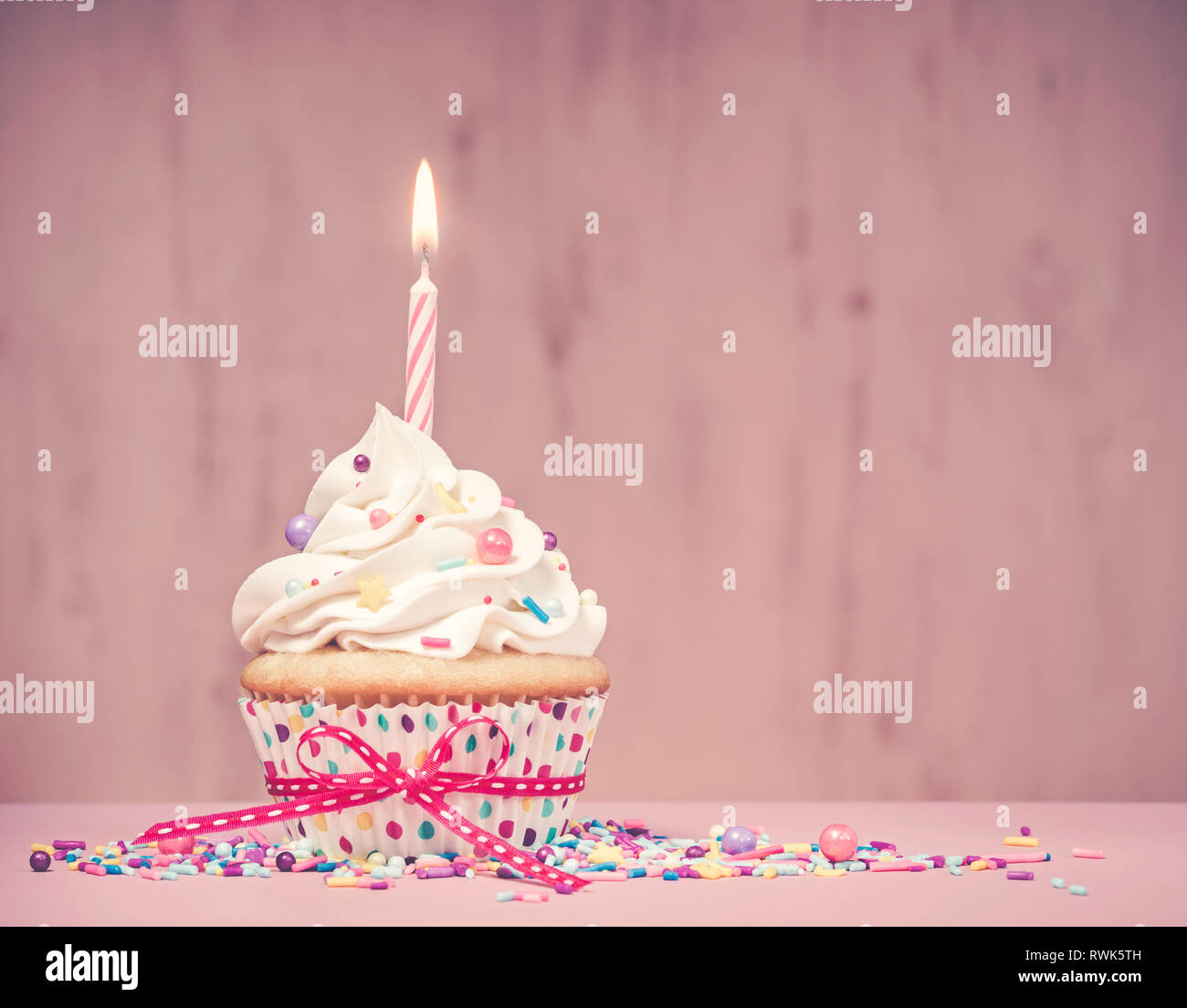 Birthday Cupcake avec bougie et saupoudre sur un fond rose. Effet Antique ajouté. Banque D'Images