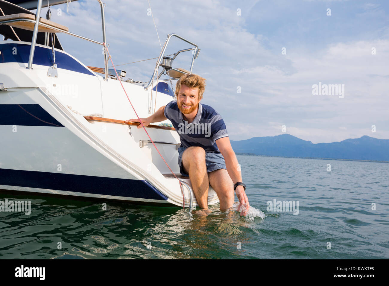 Young man leaning de voilier sur le lac de Chiemsee, portrait, Bavière, Allemagne Banque D'Images