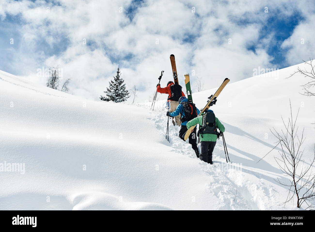 Les skieurs hommes voguant vers le haut de la montagne couverte de neige, vue arrière, Alpe-d'Huez, Rhône-Alpes, France Banque D'Images