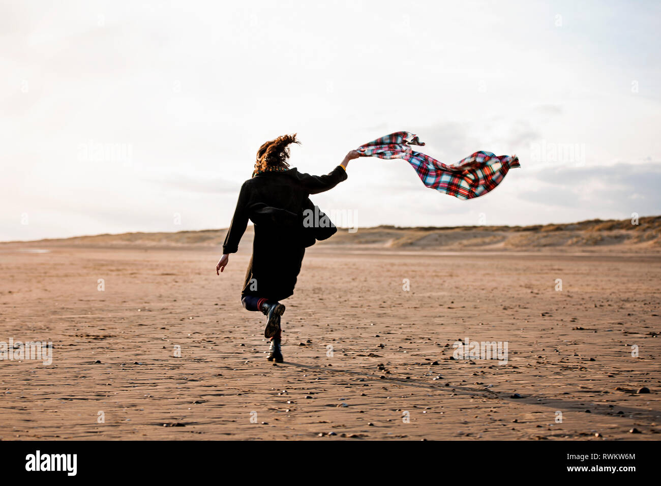 Woman running with beach blanket Banque D'Images