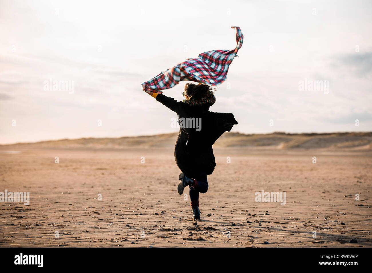 Woman running with beach blanket Banque D'Images