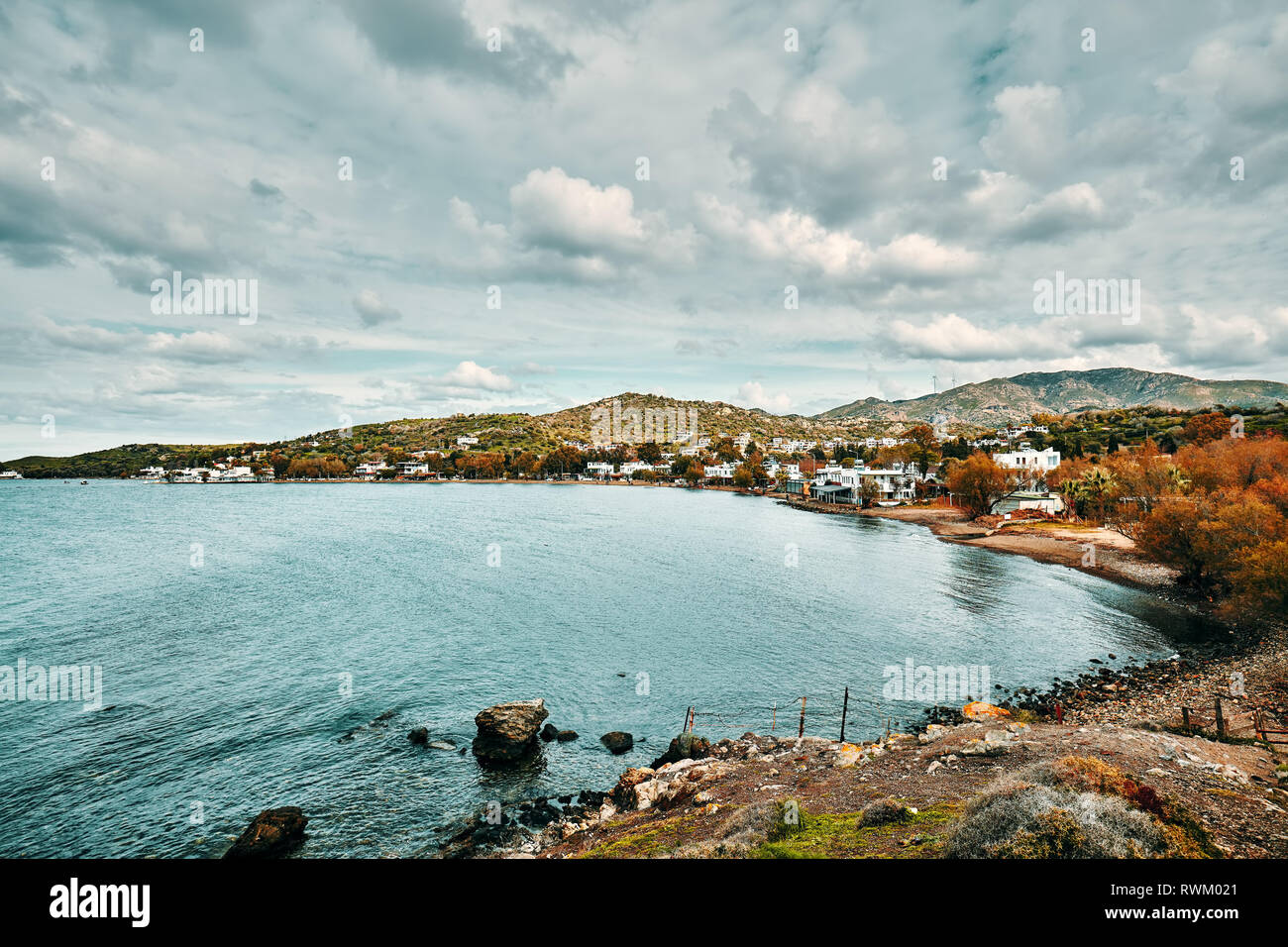 Vue de la baie de Gumusluk Moody et village de Bodrum, Mugla, Turquie sur une journée d'hiver. Belle mer calme, prairie et ciel paysage. Banque D'Images
