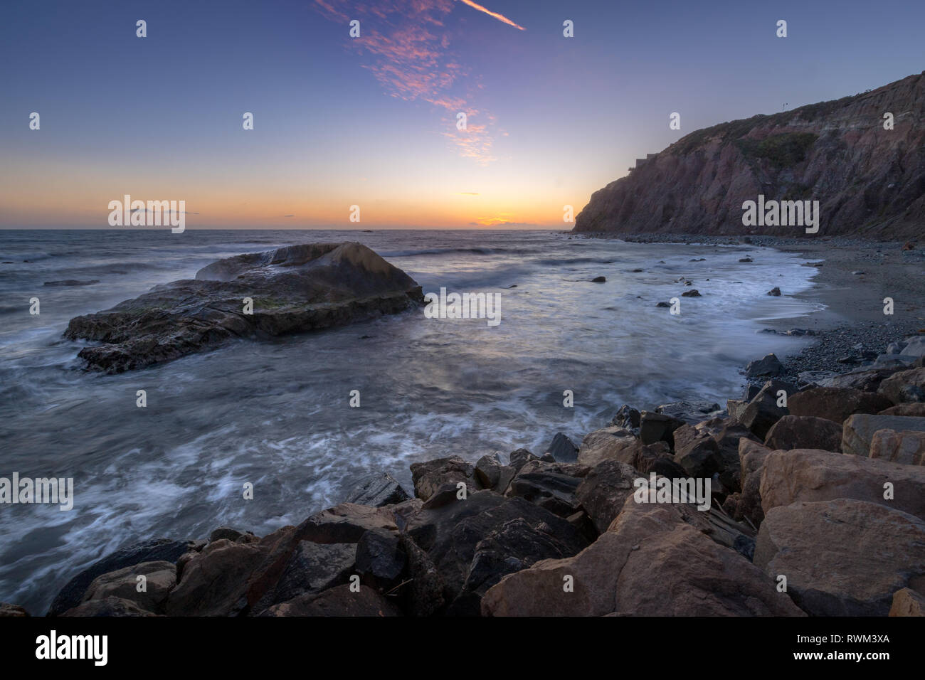 Une longue exposition photo de substitution, de hautes falaises et les vagues s'écraser dans un grand rock formation après le coucher du soleil, Dana Point, Californie Banque D'Images