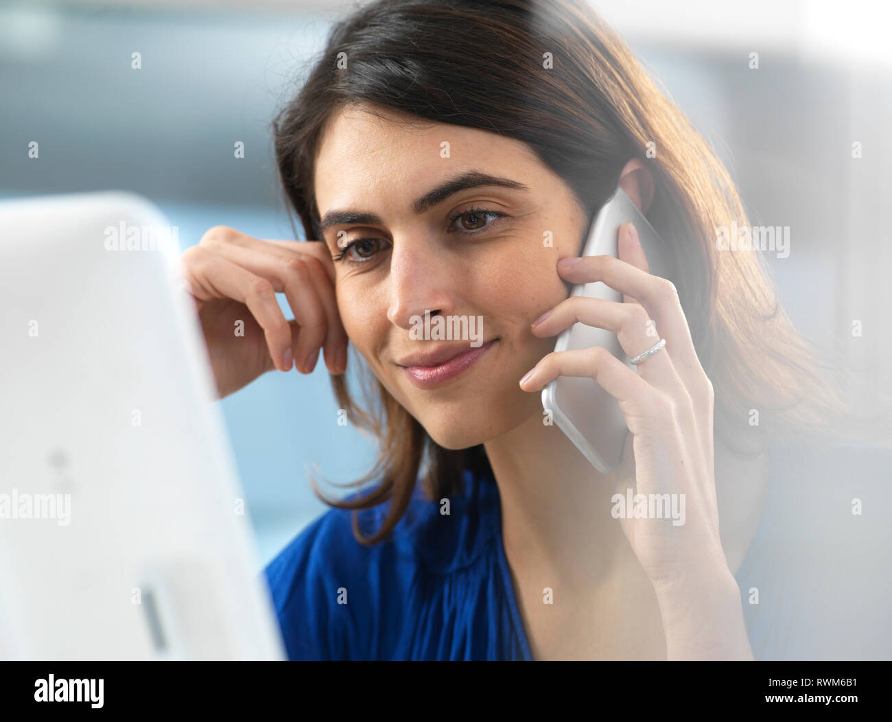 Femme travaillant à l'ordinateur et à l'aide de mobile phone in office Banque D'Images