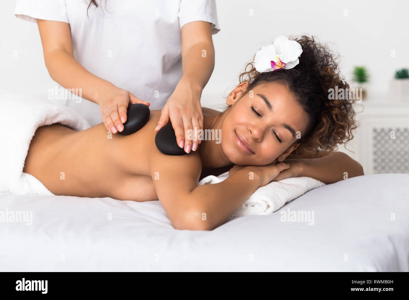 Relaxed woman getting épaule pierres massage in spa Banque D'Images