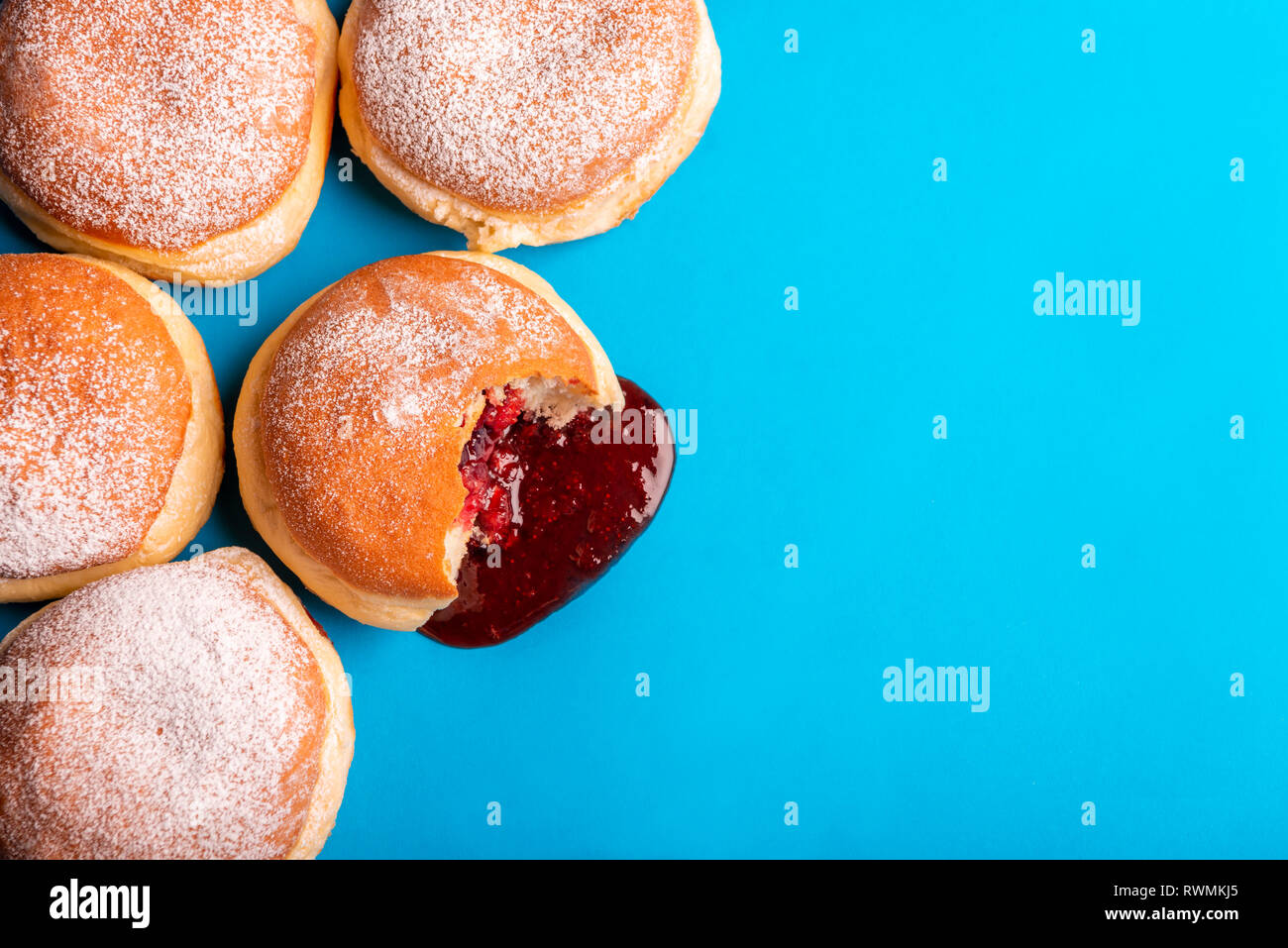 Bande de confiture beignets, rempli de gelée de fraises, couvert de sucre en poudre, sur un fond de papier bleu. Mise à plat avec un aliment sucré. Banque D'Images