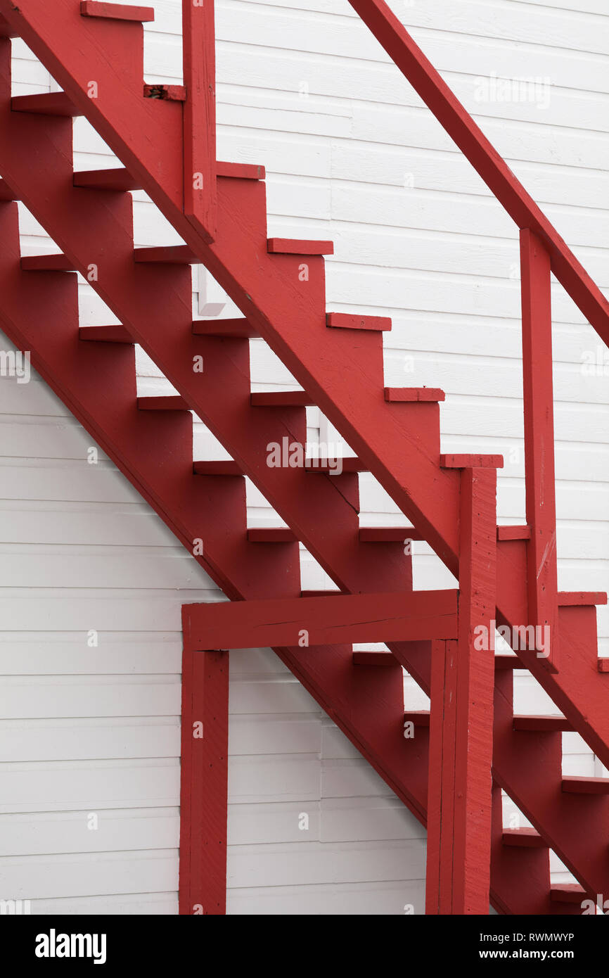 Image abstraite de l'escalier en bois rouge contre un mur blanc Banque D'Images
