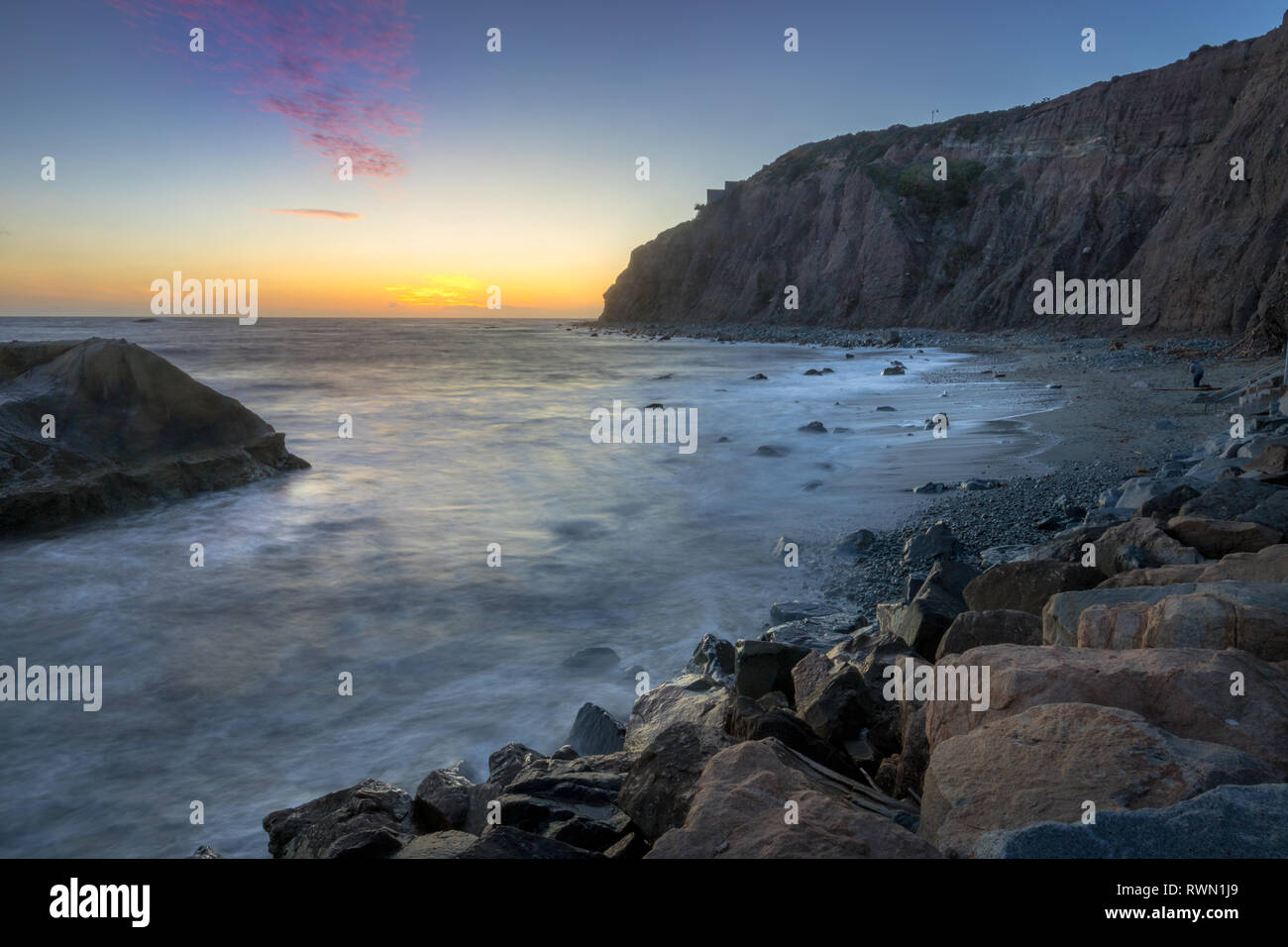 Une longue exposition photo de substitution, de hautes falaises et les vagues s'écraser dans un grand rock formation après le coucher du soleil, Dana Point, Californie Banque D'Images