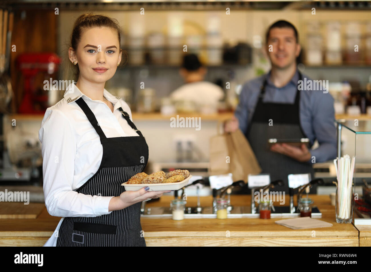 Jeune femme et homme travaillant dans un restaurant. Derrière la cuisine Banque D'Images