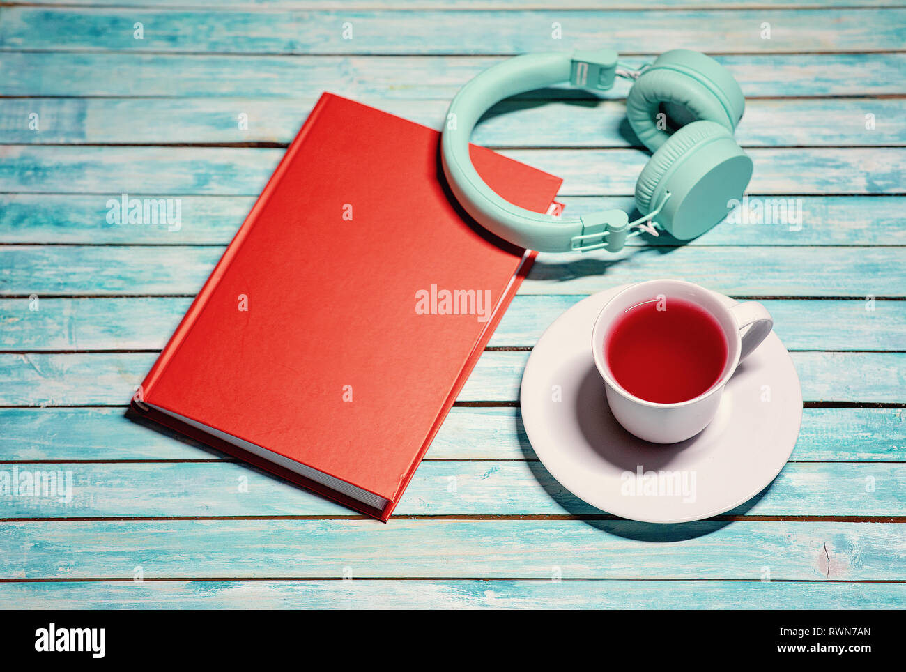 Plus de casque livre rouge. Tasse de thé. Table en bois. La lecture et les livres audio concept Banque D'Images
