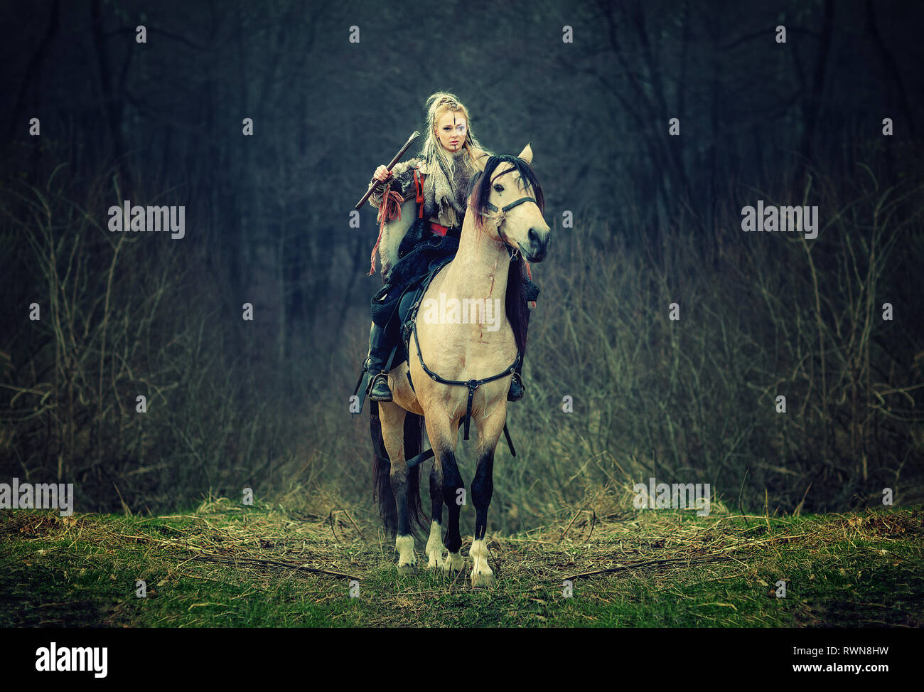 Femme guerrière sur un cheval dans les bois. beau cheval viking scandinave la hache à la main, cheveux blonds en vêtements traditionnels avec la fourrure colla Banque D'Images