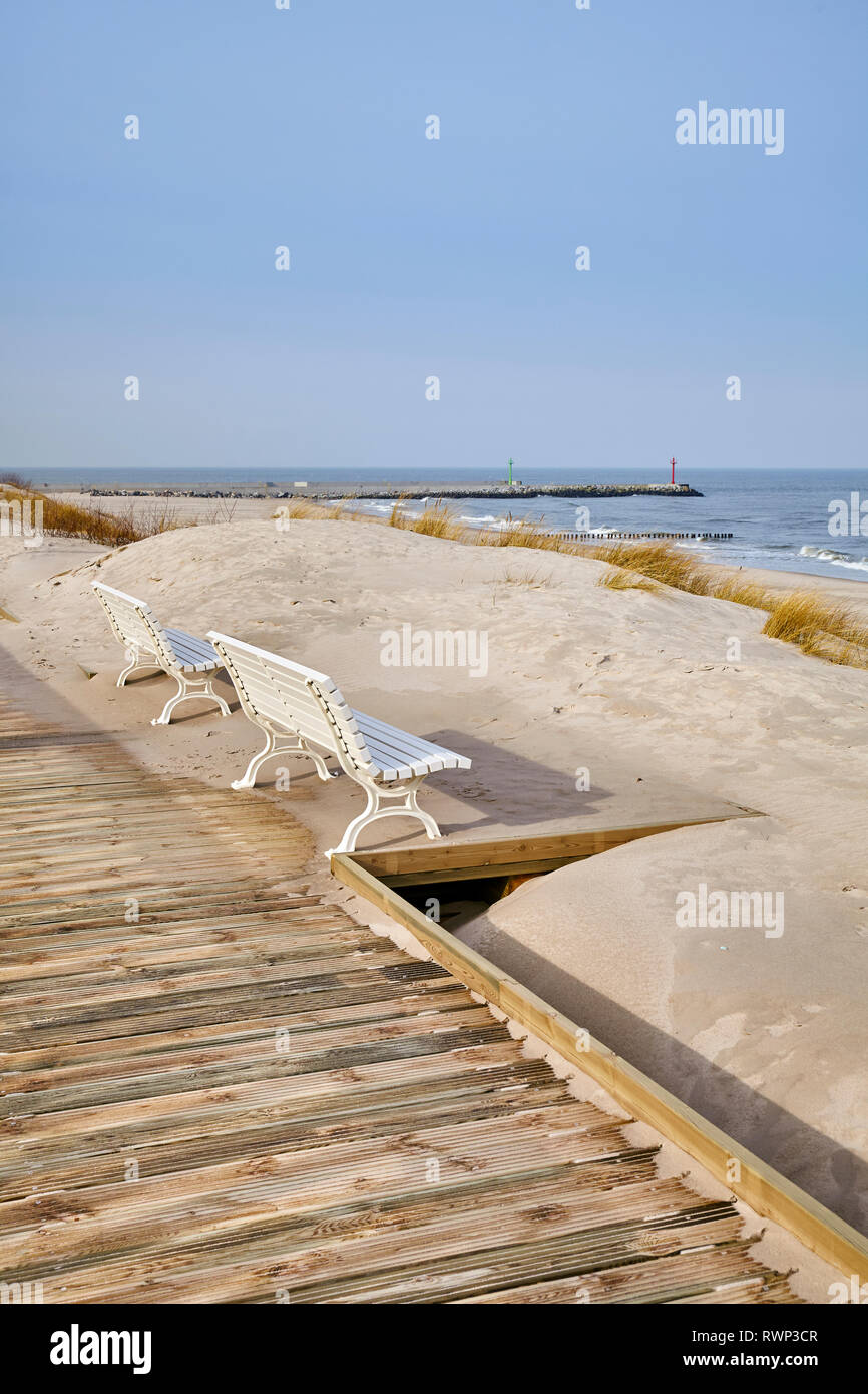 Des bancs le long d''une vue sur la mer promenade en bois sur une journée ensoleillée. Banque D'Images