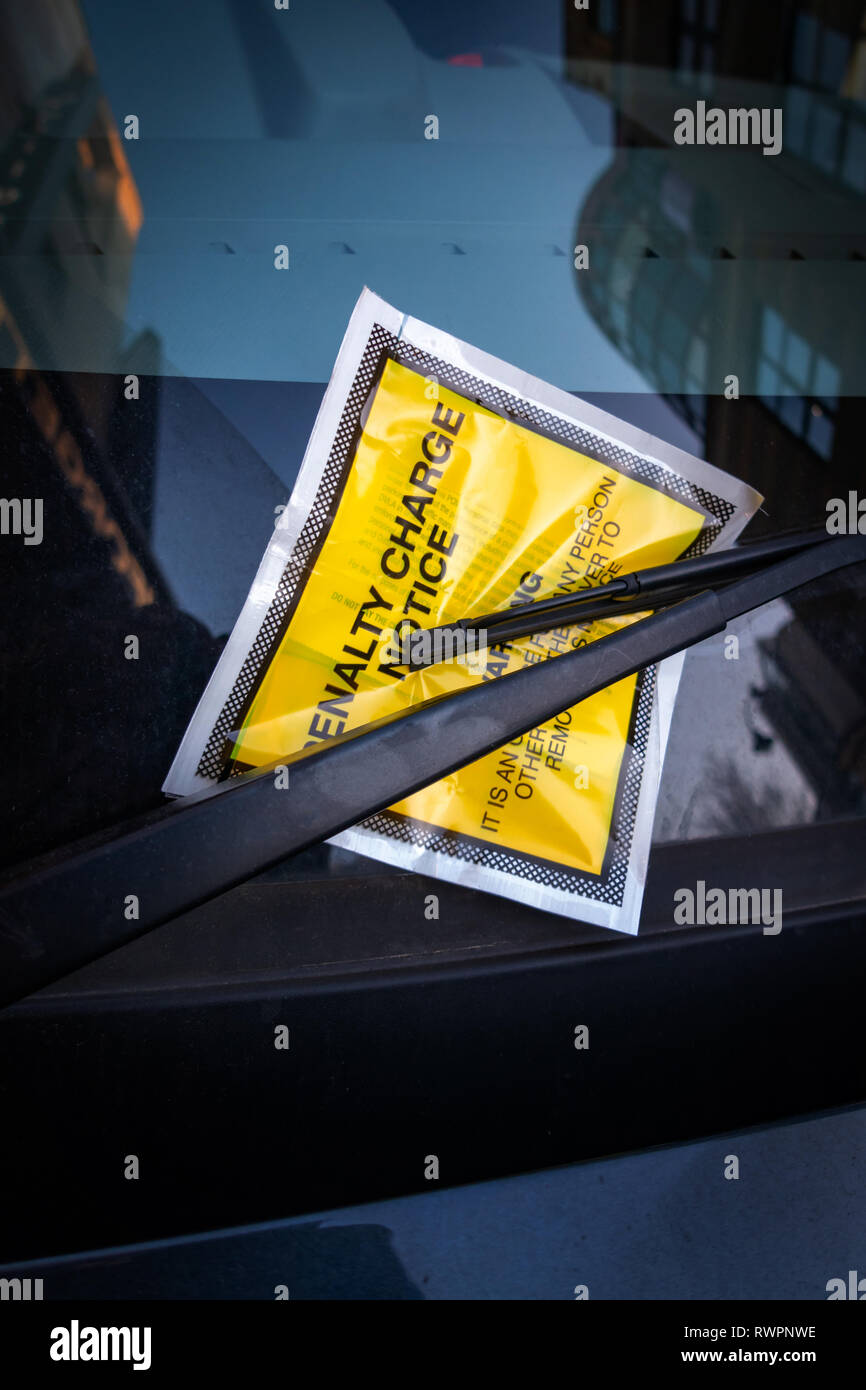 Autocollant de pare-brise jaune contenant une peine fixe Avis Parking pour stationnement illégal frais fine collée sur un pare-brise de voiture. Banque D'Images