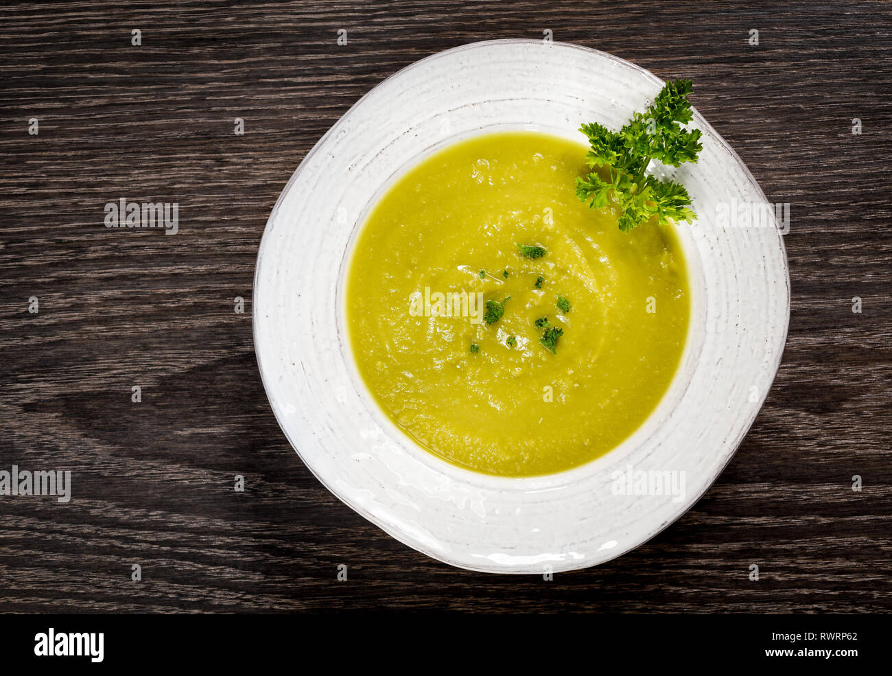 Soupe aux pois vert dans un bol blanc sur un fond de bois sombre. Banque D'Images