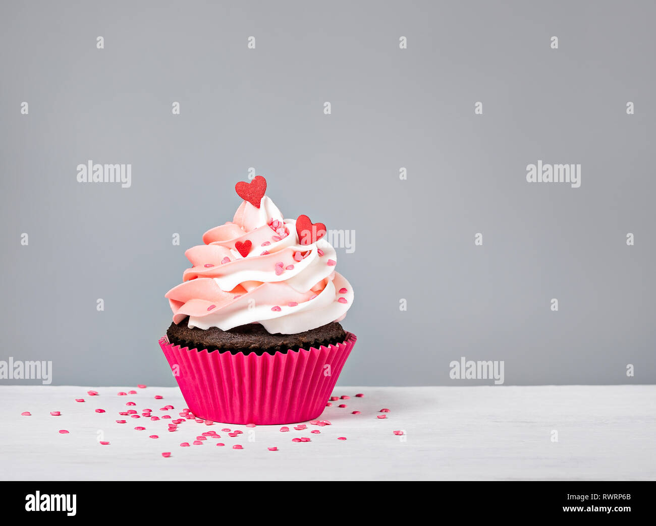 Valentines Day Cupcake traiter avec glaçage buttercream et coeur saupoudre sur fond gris Banque D'Images