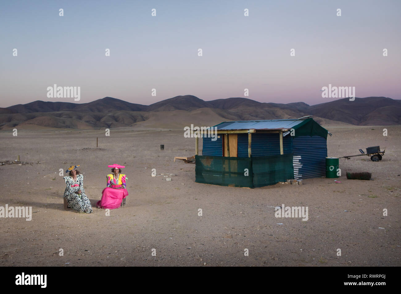 Les femmes Herero s'asseoir à l'extérieur d'une maison dans la région de Kunene, Purros, la Namibie. Banque D'Images
