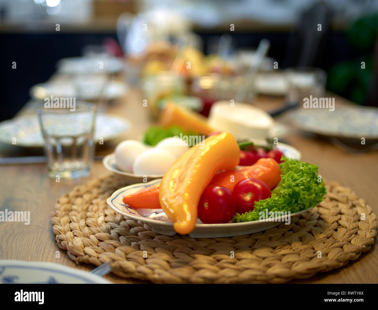 Set de table en bois pour le petit-déjeuner avec des fruits, légumes, confiture en face d'une cuisine, l'accent sur les poivrons dans l'avant-plan Banque D'Images