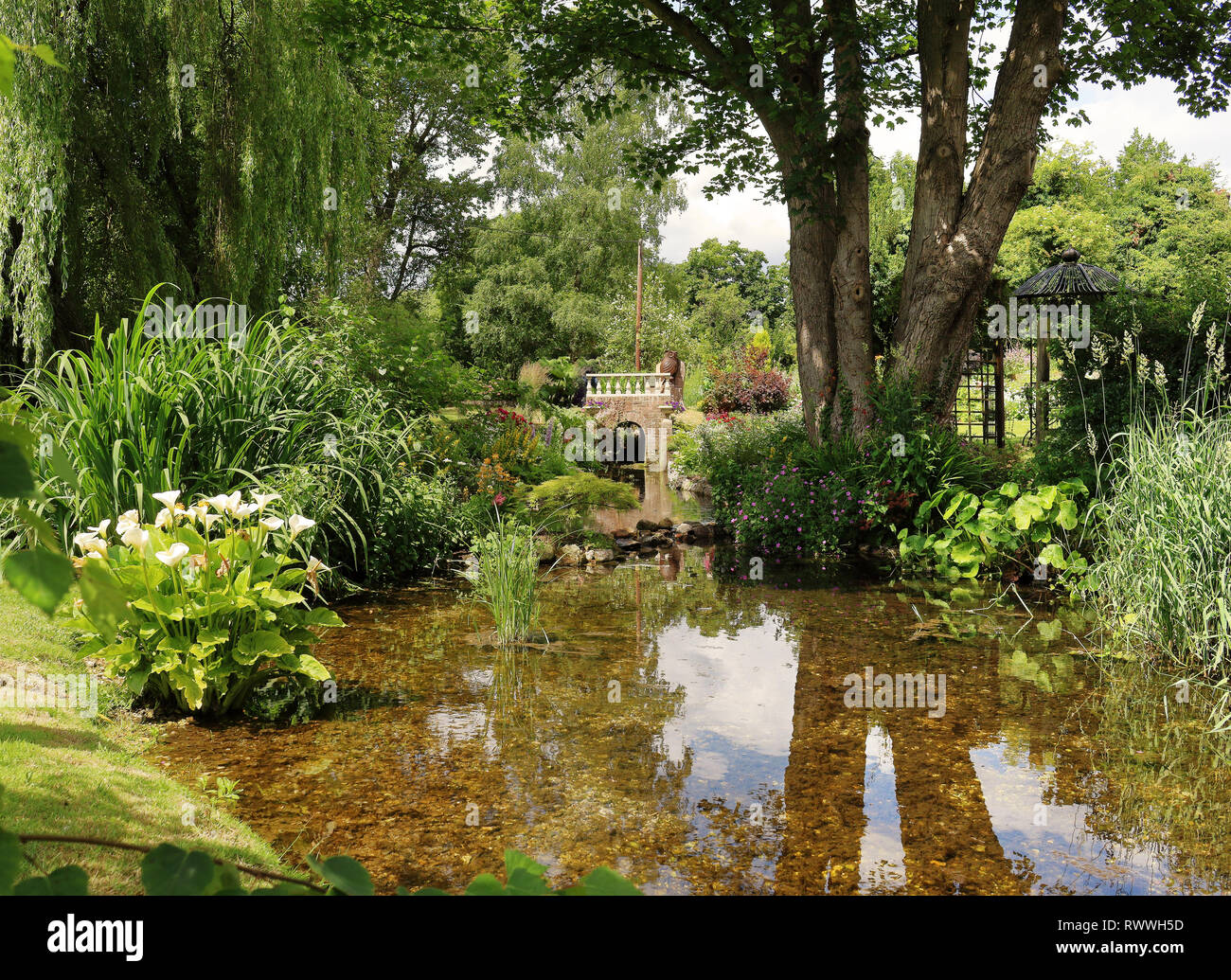 Jardin verdoyant avec ruisseau et petit pont de pierre Banque D'Images