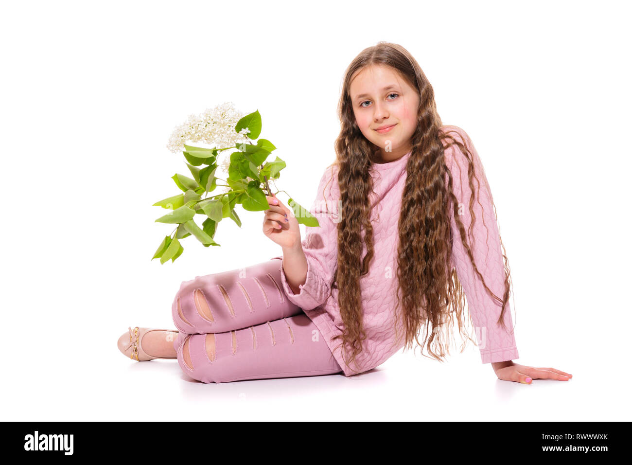 Smiling girl 10-11 ans dans un costume rose lilas blanc tenant dans ses mains. L'isolement sur un fond blanc Banque D'Images