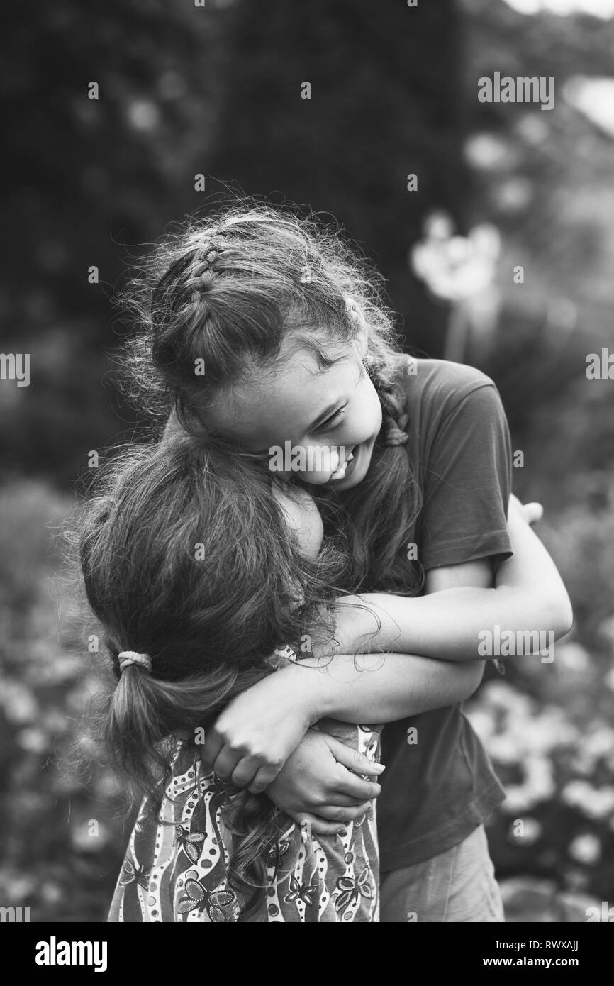 Portrait noir et blanc de deux petites filles rire heureux et s'étreindre au parc d'été. Banque D'Images