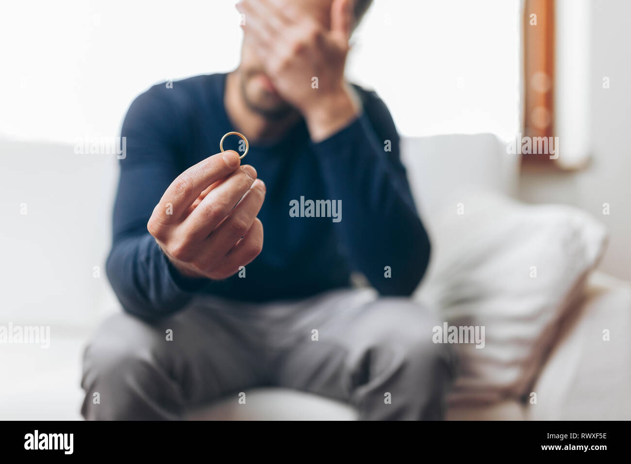 Le cœur brisé à la maison de l'homme tenant un anneau de mariage Banque D'Images