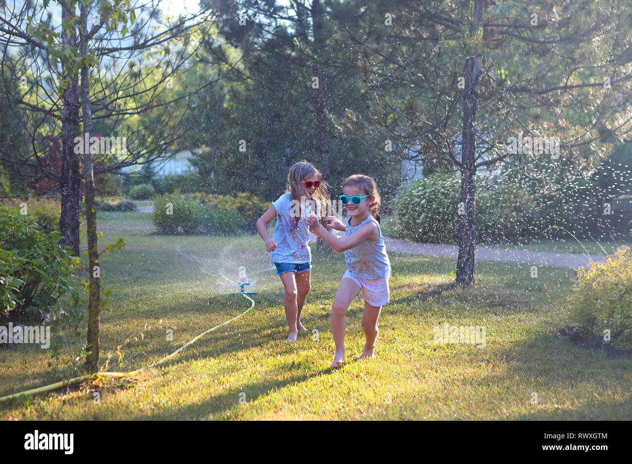 Enfant jouant avec jardin arroseur. Les enfants courir et sauter. Piscine d'été de plaisir de l'eau dans la cour. Les enfants jouent avec le tuyau arrosage des fleurs. Kids splas Banque D'Images