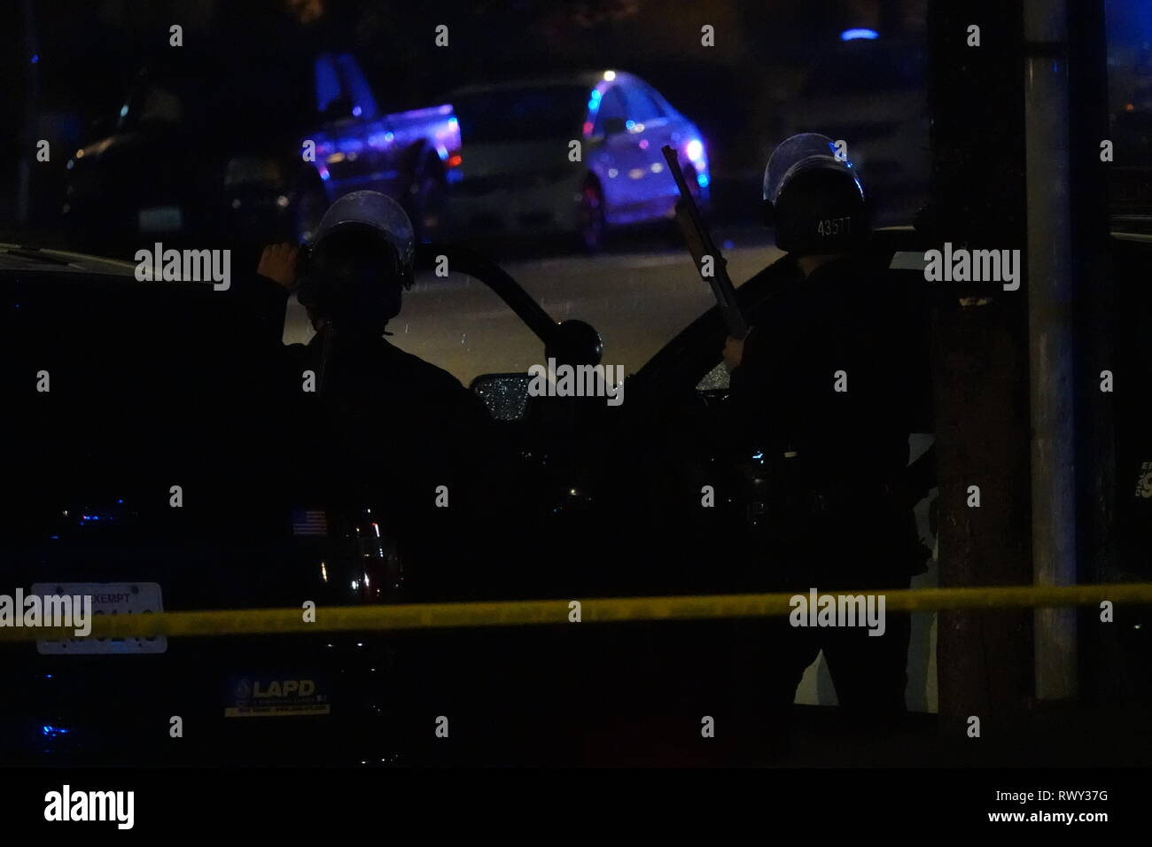Los Angeles, CA / USA - 6 mars 2019 : Deux Los Angeles Police Department (LAPD) aka les officiers sont indiqués en attente durant un face-à-face à une résidence sur Burbank Blvd. dans le Nord d'Hollywood. Les deux officiers portent des casques anti-émeute avec des masques, et l'un est montré tenant un fusil de chasse. Credit : Kilmer Media/Alamy Live News Banque D'Images