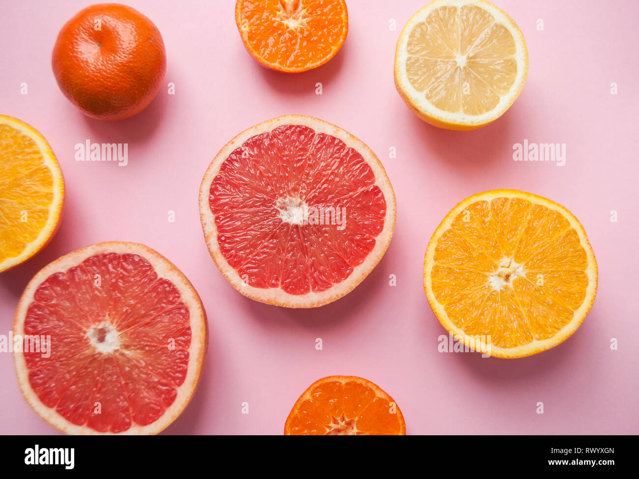 Mise à plat de coupe juteuse mûres pamplemousse, citron et orange sur fond rose. Mise à plat de style. Banque D'Images