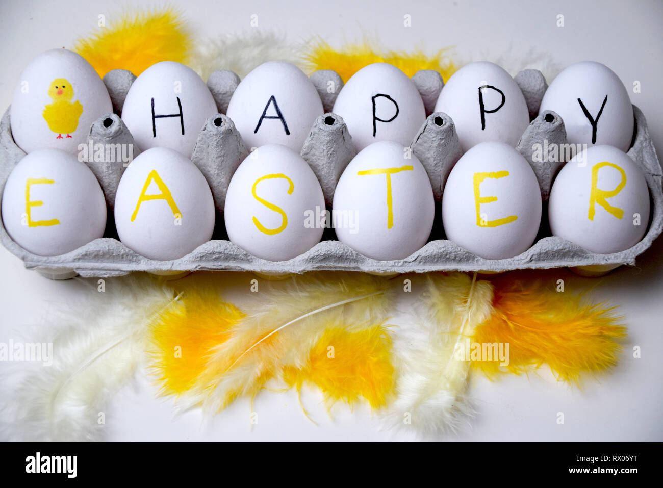 Joyeuses Pâques bonjour avec ce plaisir fort d'oeufs et de plumes jaunes sur fond blanc Banque D'Images