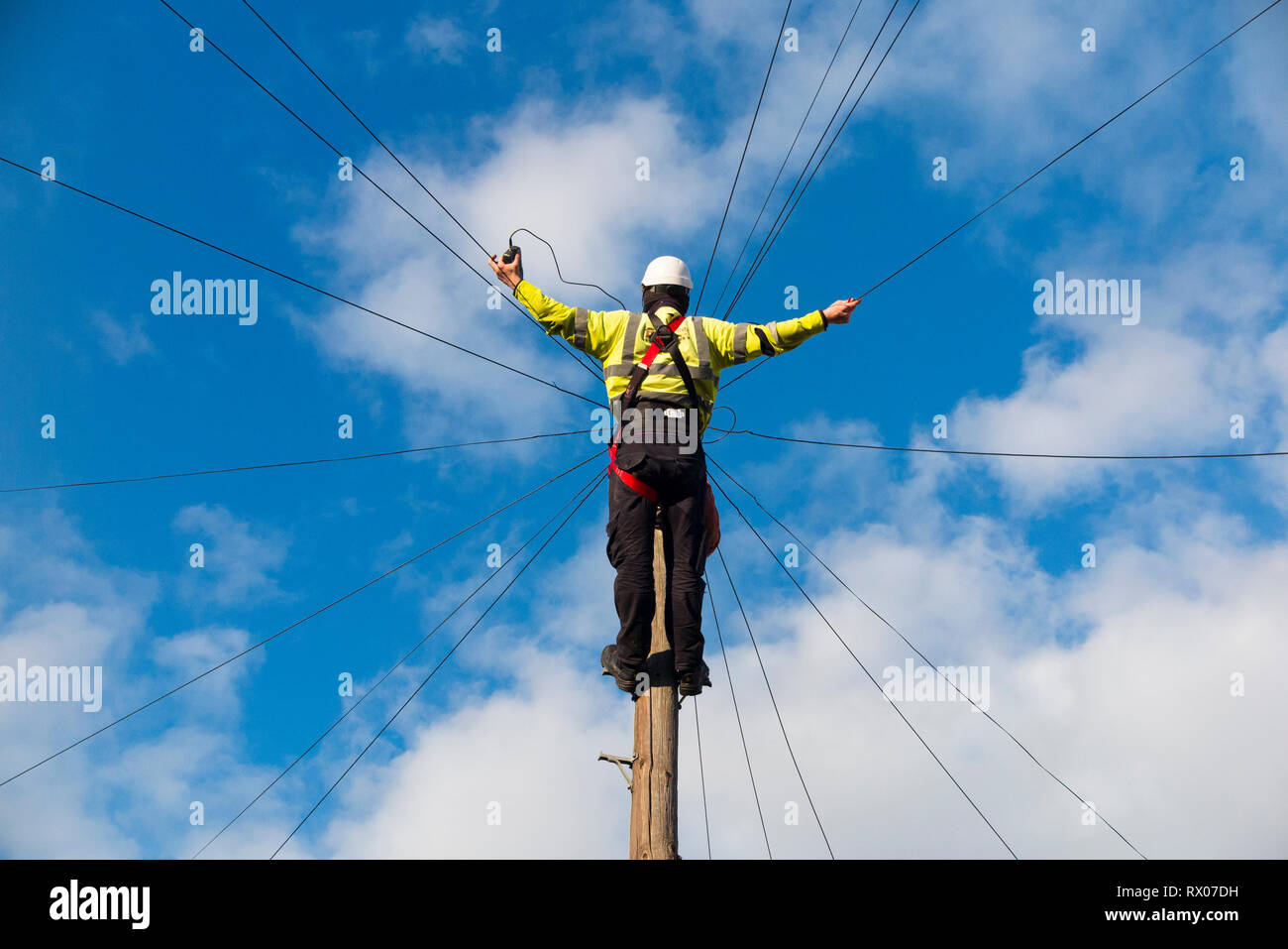 Telecom ingénieur travaillant sur la ligne de téléphone internet haut débit / d'un fil de cuivre téléphone / poteau télégraphique dans une rue de Londres / Road, et ciel bleu Banque D'Images