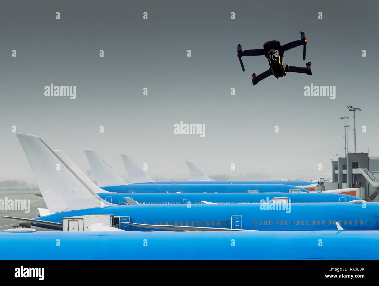 Drone sans pilote volant près de rangée d'avions commerciaux à l'aéroport, perturbation vol - concept composite numérique. Banque D'Images