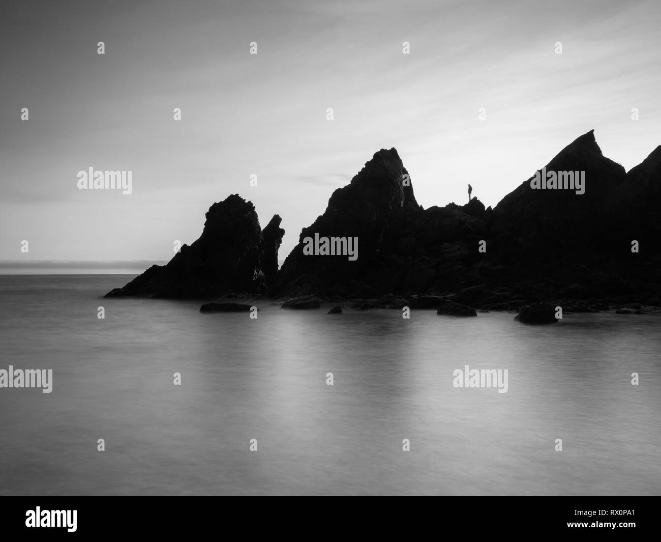 Seul un homme debout, regardant l'horizon en Soar Mill Cove au sud du Devon, UK Banque D'Images