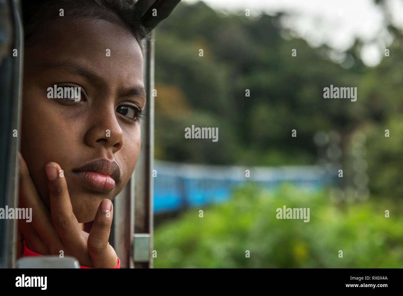 Jeune fille dans un train - un jour chaud en mars, une jeune fille bénéficie de la brise venant de la fenêtre ouverte sur le trajet en train de la gare de Nanu Oya à Ella en Sr Banque D'Images
