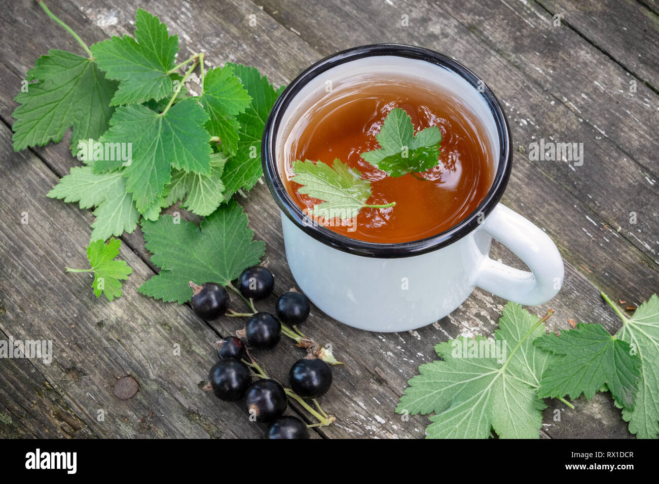 Tasse de thé fruits émaillé avec des baies de cassis sur table en bois à l'extérieur. Vue d'en haut. Banque D'Images