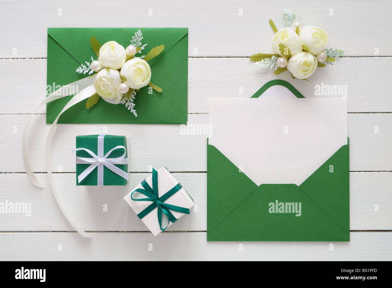 Cartes d'invitation de mariage ou de saint Valentin des lettres dans des enveloppes vert décoré de fleurs rose blanche et deux boîtes de cadeaux. Mise à plat. Vue d'en haut. S COPIE Banque D'Images